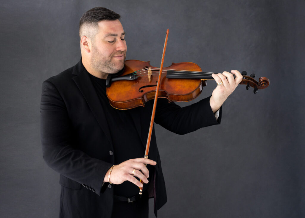 Mike in a Black Suit Holding a Violin