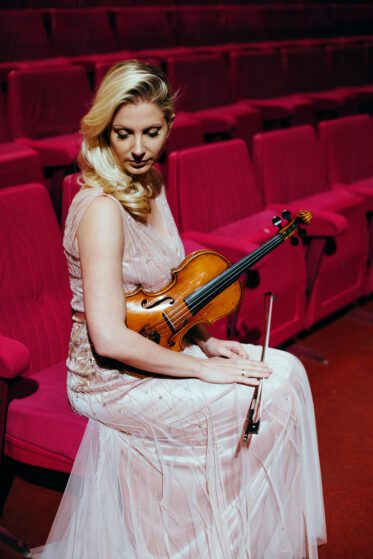 A female violinist sitting on a theater chair
